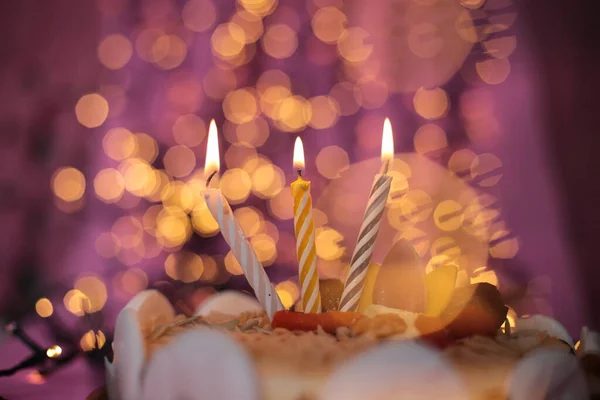 Burning candle in the cake festive bright pink background birthday macro photo