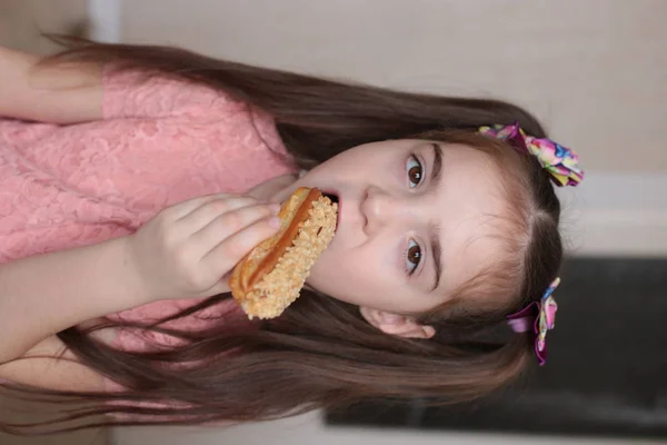 A girl of eight years old eats a tasty dessert delicious eclairs macro photo