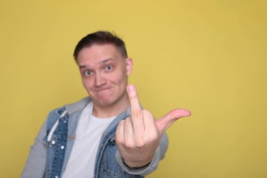 Havalı, havalı, kot giyen, parlak sarı arka planda sıradan giyinen adam.