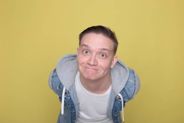 Havalı, havalı, kot giyen, parlak sarı arka planda sıradan giyinen adam.