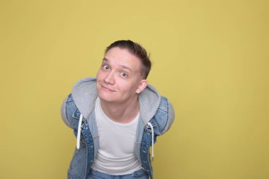 Havalı, havalı, kot giyen, parlak sarı arka planda sıradan giyinen adam.