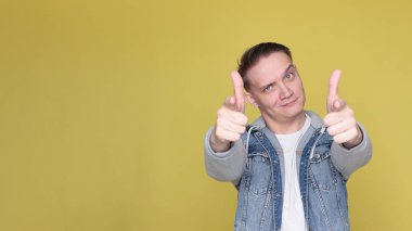 Havalı, havalı, kot giyen, parlak sarı arka planda sıradan giyinen adam.