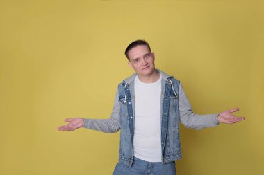 Havalı, havalı, kot giyen, parlak sarı arka planda sıradan giyinen adam.