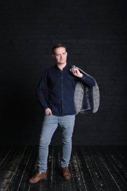 Siyah arka planda ceketli ve gömlekli duygusal bir genç adam portresi.