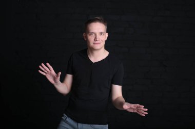 Siyah tişörtlü, siyah arka planda havalı, havalı bir genç adam portresi.