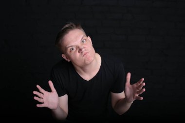 Siyah tişörtlü, siyah arka planda havalı, havalı bir genç adam portresi.