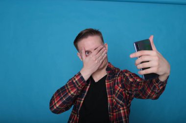 Siyah tişörtlü, parlak mavi arka planlı, kareli tişörtlü şık, şık, şık bir genç portresi.