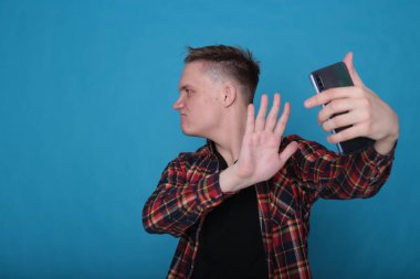 Siyah tişörtlü, parlak mavi arka planlı, kareli tişörtlü şık, şık, şık bir genç portresi.