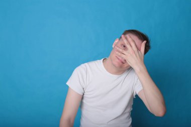 Modern portre duygusal klas, beyaz tişörtlü, parlak mavi arka planlı genç adam.