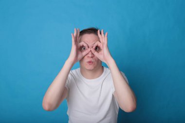 Modern portre duygusal klas, beyaz tişörtlü, parlak mavi arka planlı genç adam.