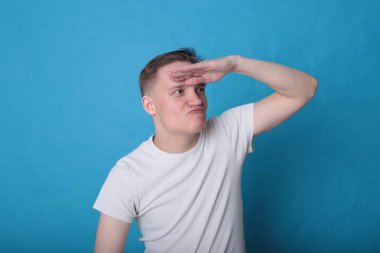 Modern portre duygusal klas, beyaz tişörtlü, parlak mavi arka planlı genç adam.