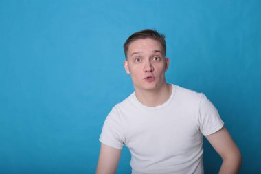 Modern portre duygusal klas, beyaz tişörtlü, parlak mavi arka planlı genç adam.