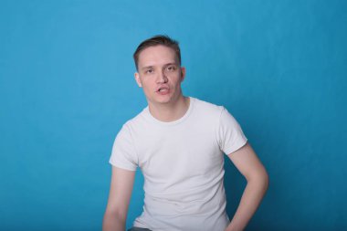 Modern portre duygusal klas, beyaz tişörtlü, parlak mavi arka planlı genç adam.