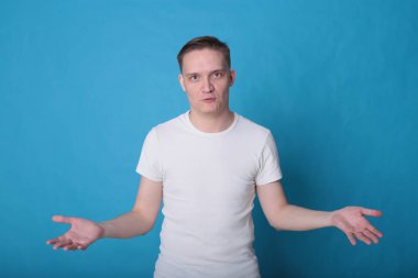 Modern portre duygusal klas, beyaz tişörtlü, parlak mavi arka planlı genç adam.