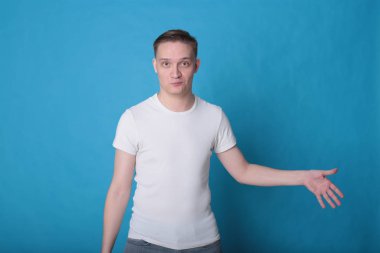 Modern portre duygusal klas, beyaz tişörtlü, parlak mavi arka planlı genç adam.