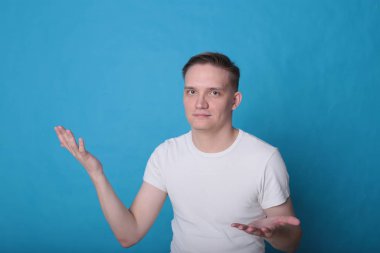 Modern portre duygusal klas, beyaz tişörtlü, parlak mavi arka planlı genç adam.