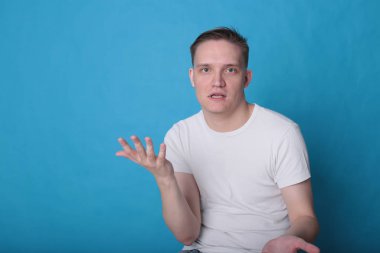 Modern portre duygusal klas, beyaz tişörtlü, parlak mavi arka planlı genç adam.