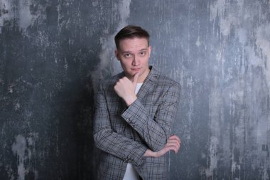 Beyaz tişörtlü ve ceketli şık bir gencin parlak bir arkaplanda ilginç bir portresi.