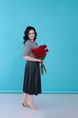 Parlak turkuaz arka planda çizgili bluzu ve pileli eteği olan güzel genç bir kadın.