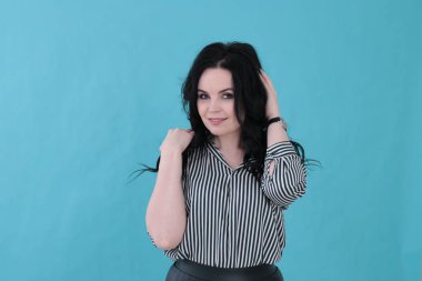 Parlak turkuaz arka planda çizgili bluzu ve pileli eteği olan güzel genç bir kadın.