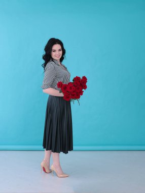 Parlak turkuaz arka planda çizgili bluzu ve pileli eteği olan güzel genç bir kadın.