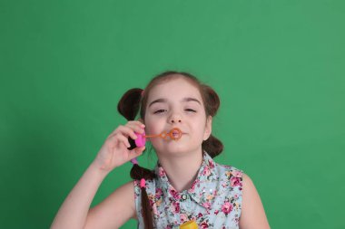 Gülümseyen, sekiz yaşında güzel bir kız. Mükemmel bir ruh hali içinde. Mavi bluzlu, çiçekli komik bir saç stili var.