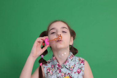 Gülümseyen, sekiz yaşında güzel bir kız. Mükemmel bir ruh hali içinde. Mavi bluzlu, çiçekli komik bir saç stili var.