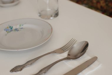 Günlük kullanım için temiz mutfak aletleri, beyaz masa arkasındaki boş tabaklar.