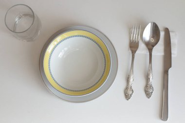 Günlük kullanım için temiz mutfak aletleri, beyaz masa arkasındaki boş tabaklar.