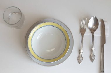 Günlük kullanım için temiz mutfak aletleri, beyaz masa arkasındaki boş tabaklar.