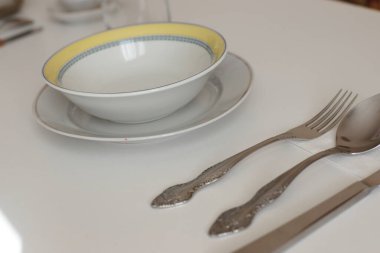 Günlük kullanım için temiz mutfak aletleri, beyaz masa arkasındaki boş tabaklar.