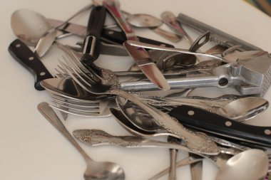 Günlük kullanım için temiz mutfak aletleri, beyaz masa arkasındaki boş tabaklar.