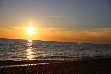 Denizde parlak, güzel bir gün batımı çimen ve çavdar kulakları, karanlık ön plan, parlak renkli şafak..