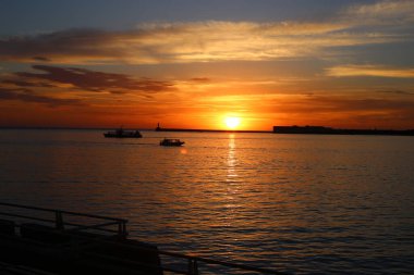 Denizde parlak, güzel bir gün batımı çimen ve çavdar kulakları, karanlık ön plan, parlak renkli şafak..