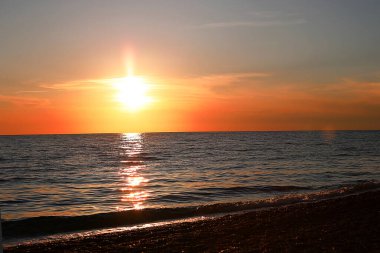 Denizde parlak, güzel bir gün batımı çimen ve çavdar kulakları, karanlık ön plan, parlak renkli şafak..