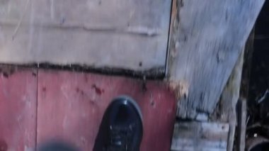 Lastik çizmeli bir adamın ayakları çamurda yürür.