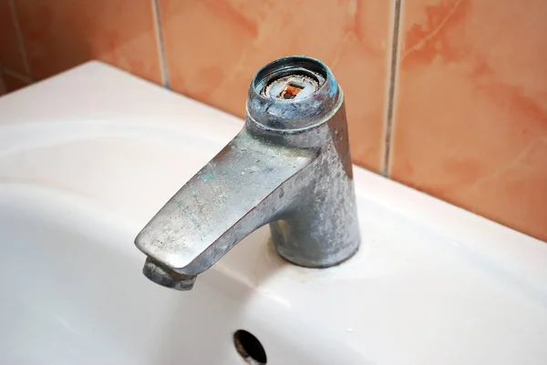 Old broken faucet mixer tap on bathroom sink.