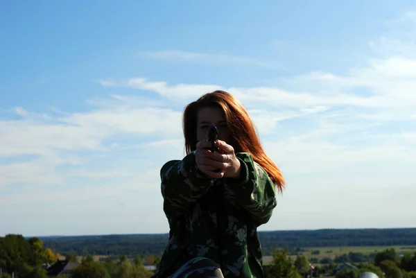一个年轻迷人的女孩穿着迷彩服 一头长长的红头发 在开枪之前瞄准 瞄准镜框 全副武装 非常危险 — 图库照片