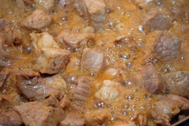 Dilimlenmiş domuz eti parçaları soya sosunda haşlanır ve kendi suları kızartma tavasında pişirilir. Et tabağı-domuz yahnisi hazırlığı. Ev yemeği. Kapat..