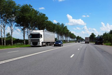 Açık bir yaz gününde Moskova otoyolunda bir araba ve bir kamyon şehir dışına çıkıyor. Araba gezisi. Yaz manzarası.