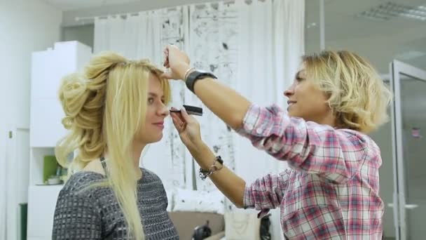 Peluquería hace peinado joven rubia mujer en un salón de belleza — Vídeos de Stock