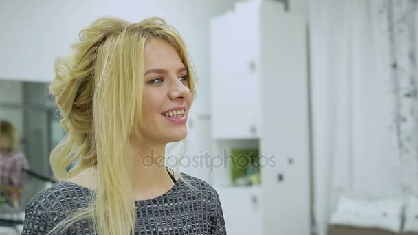 Hairdresser makes hairstyle young blonde woman in a beauty salon — Stock Video