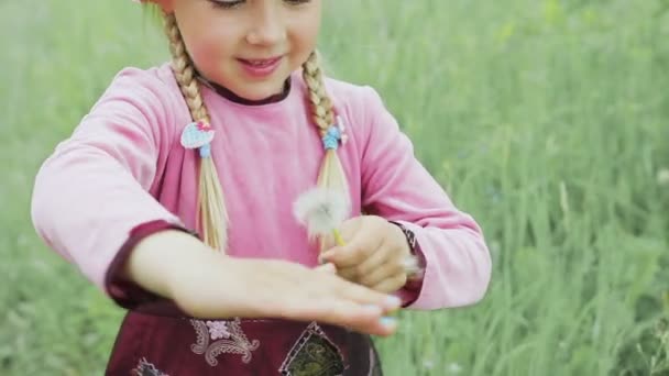 Een klein meisje wegblaast paardebloem — Stockvideo