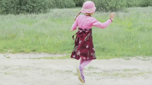 Een klein meisje loopt over het veld — Stockvideo
