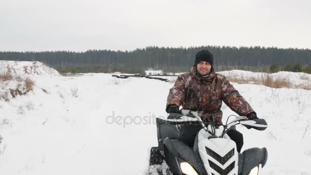 El tipo está montando un ATV en un camino cubierto de nieve en invierno — Vídeo de stock