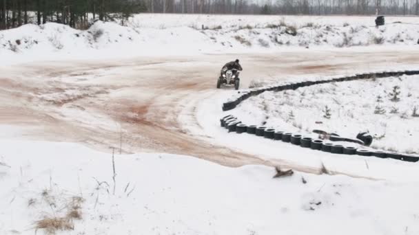Il ragazzo sta cavalcando un ATV su una strada innevata in inverno — Video Stock