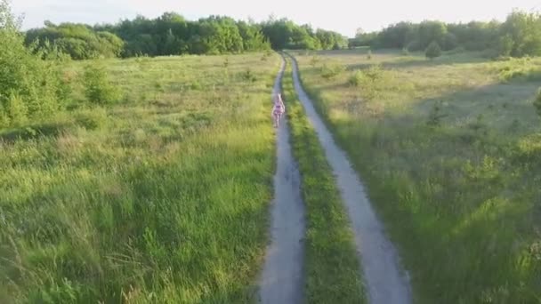 Маленькая девочка в белом сарафане с красными узорами бежит по полю — стоковое видео