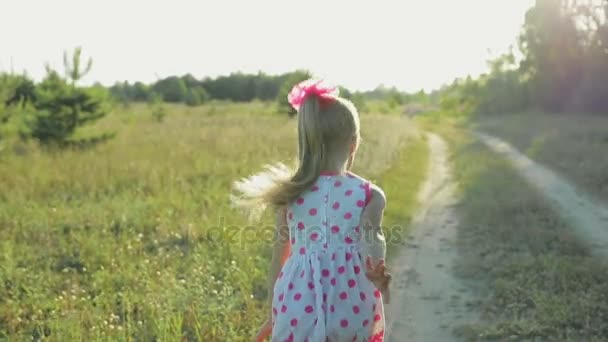 Menina em um vestido branco com padrões vermelhos correndo pelo campo — Vídeo de Stock