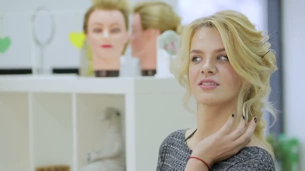 Schattige blonde meisje kijkt in de spiegel in de schoonheidssalon — Stockvideo