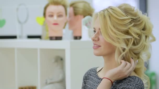 Милая блондинка смотрит в зеркало в салоне красоты — стоковое видео
